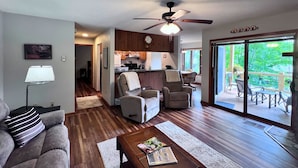A spacious living room with a sofa, armchairs, and a coffee table. A kitchen is visible in the background with wooden cabinets and a dining area. - Charming two-bedroom, two-bathroom condo minutes away from Sugar Mnt. Resort (Sugar Mountain)