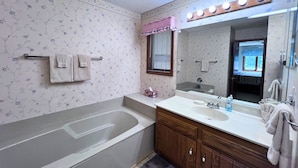 A bathroom with a bathtub, vanity with a mirror, and floral wallpaper. - Charming two-bedroom, two-bathroom condo minutes away from Sugar Mnt. Resort (Sugar Mountain)