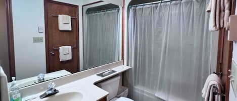 A bathroom with a sink, toilet, and shower curtain.