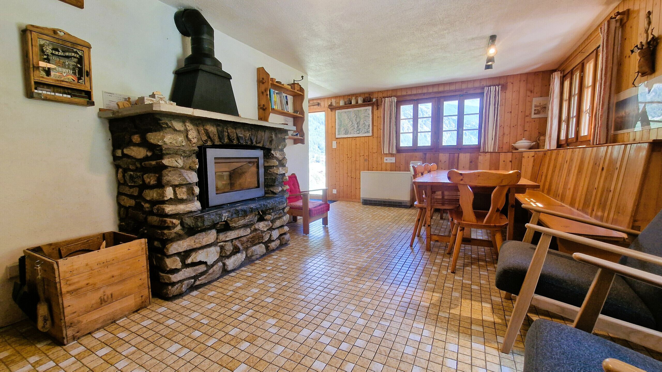 A cozy room with a stone fireplace, wooden furniture, and a tiled floor.