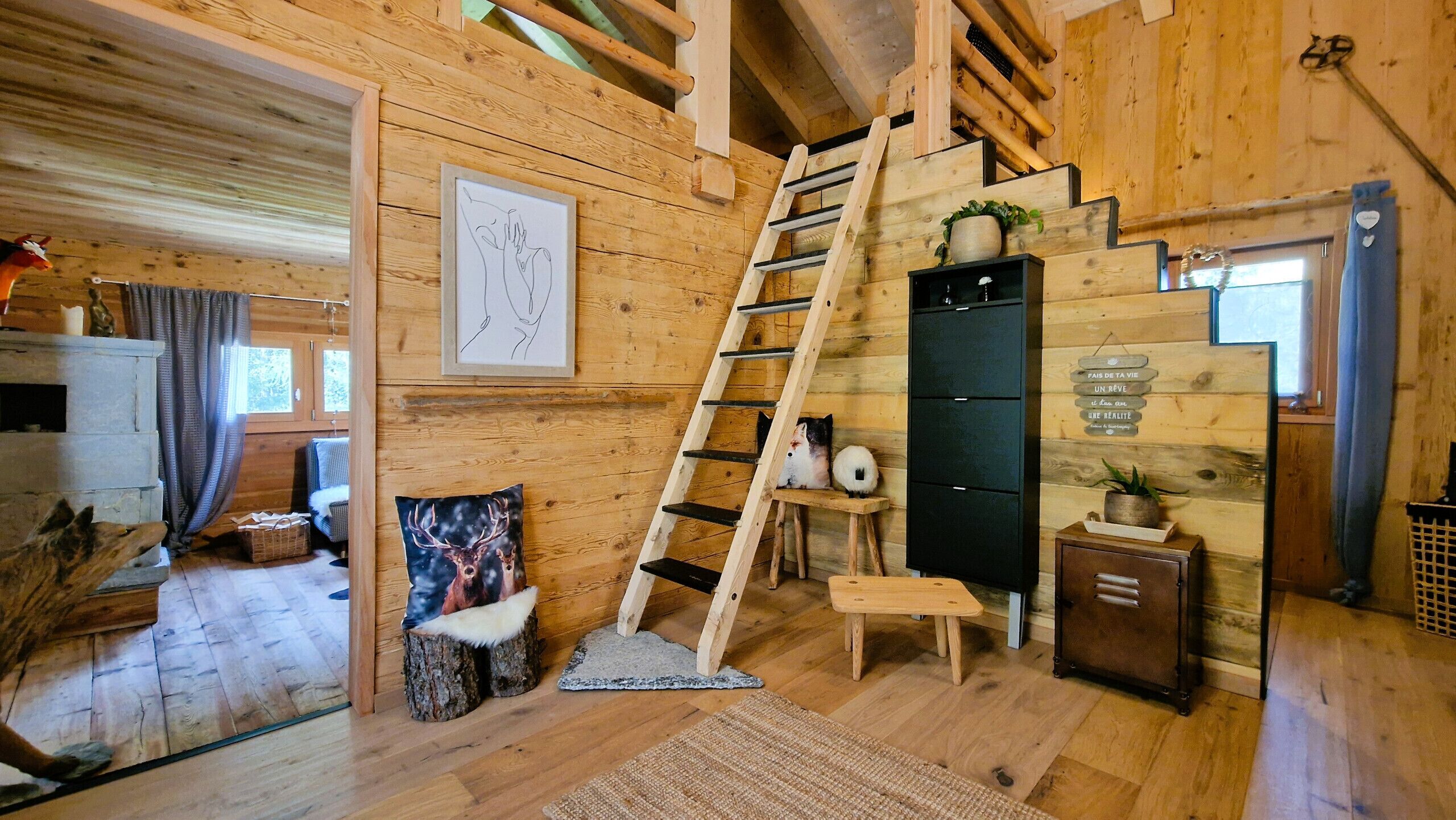 Un intérieur en bois avec un escalier en bois, une cheminée et un tableau encadré au mur.