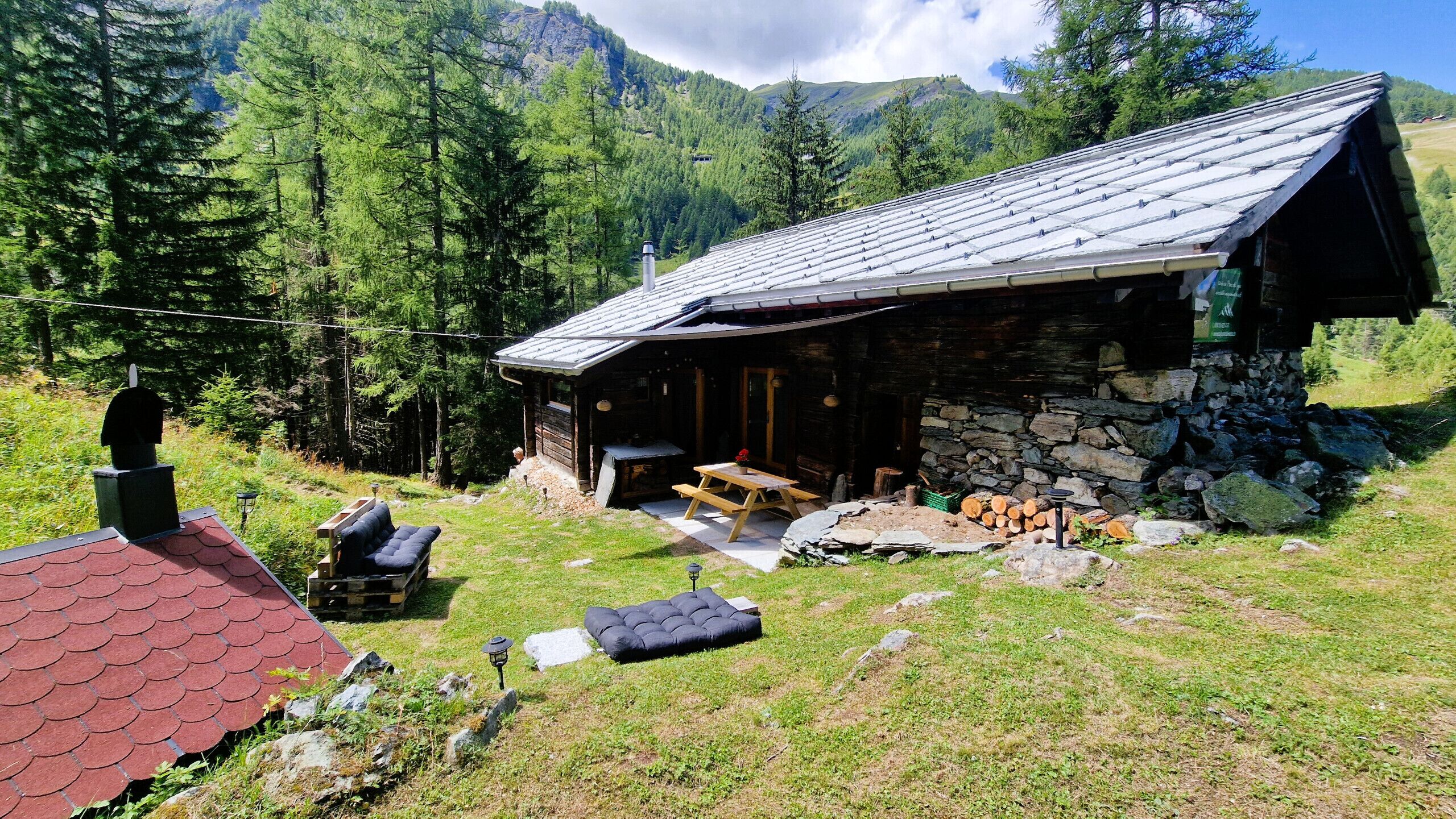Un chalet rustique avec une façade en pierre, une terrasse en bois et une cheminée en pierre.