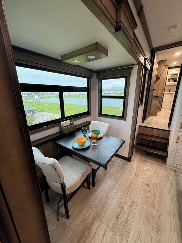 Un comedor con mesa, sillas y vista a un lago.