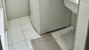 A compact laundry room with a washing machine, a sink, and a window. - Apartment in front of Colinas shopping mall (Jardim das Colinas São José dos Campos)