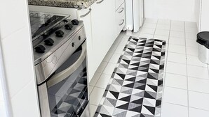 A modern kitchen with white cabinets, a granite countertop, a built-in oven, a gas stove, a refrigerator, and a patterned floor. - Apartment in front of Colinas shopping mall (Jardim das Colinas São José dos Campos)