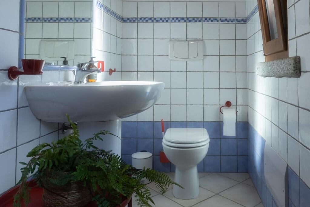 Un baño con un lavamanos blanco, un inodoro y un espejo.