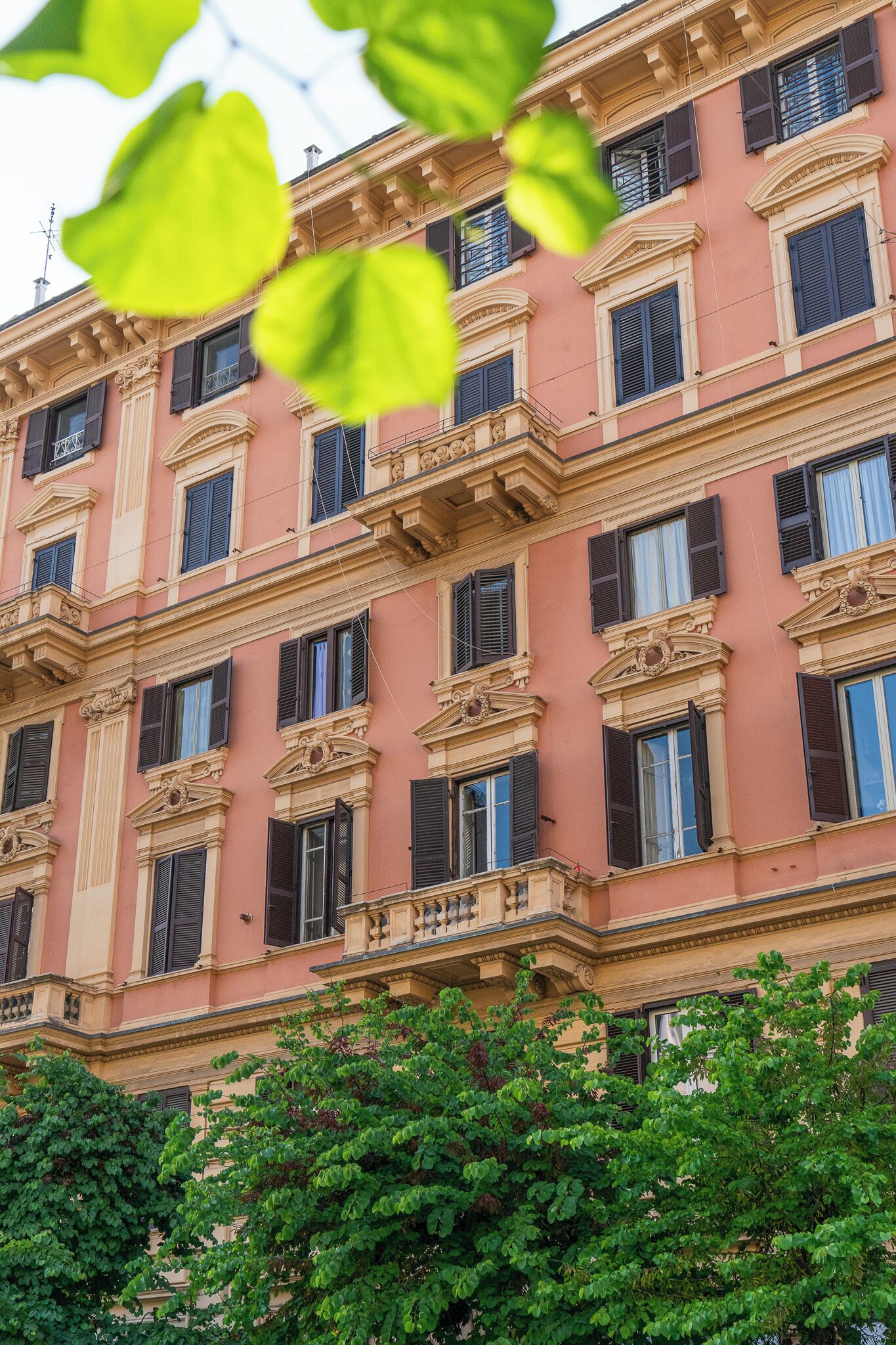 A multi-story building with a pink facade, multiple windows with shutters, and balconies.