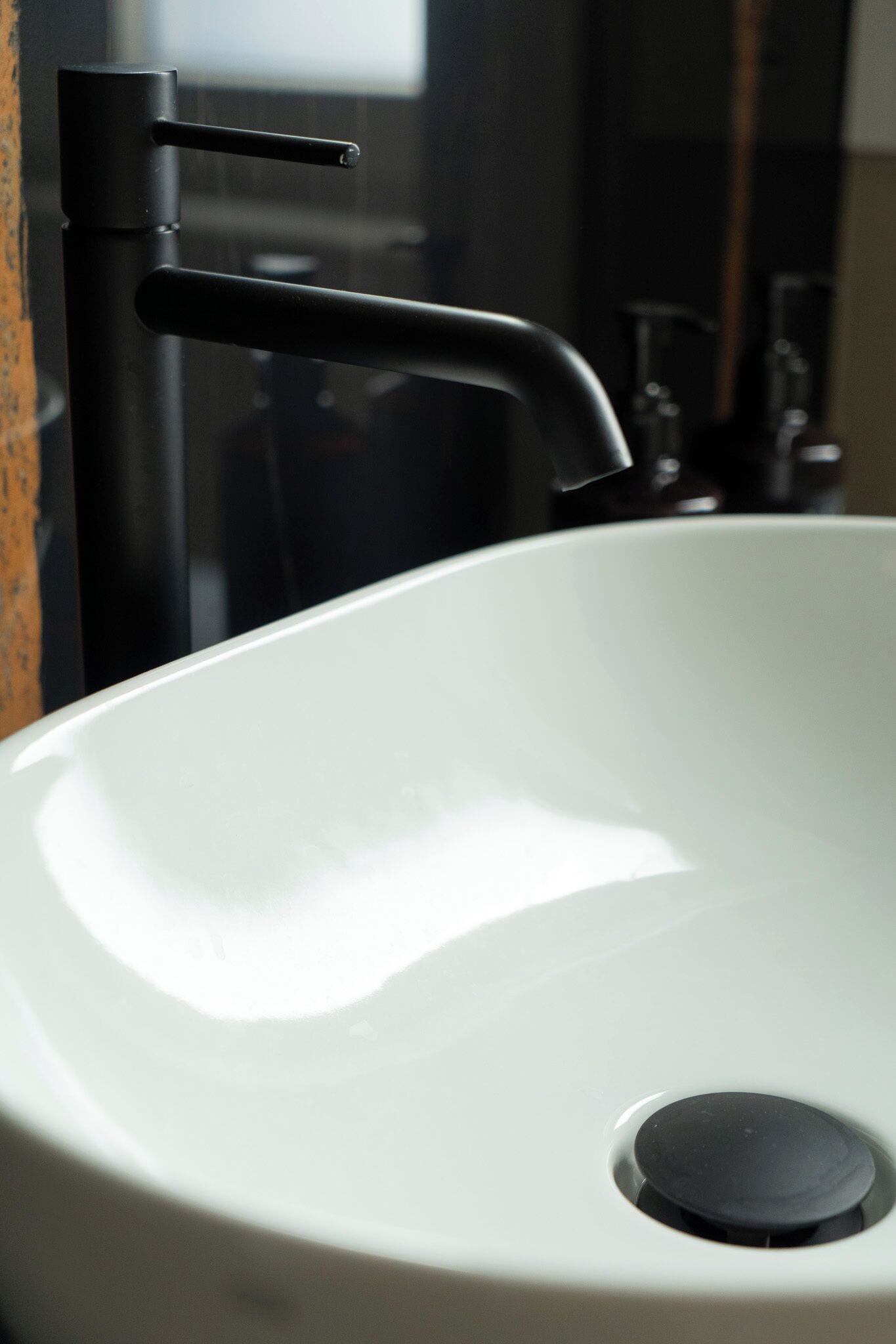 A white sink with a black faucet and a drain.