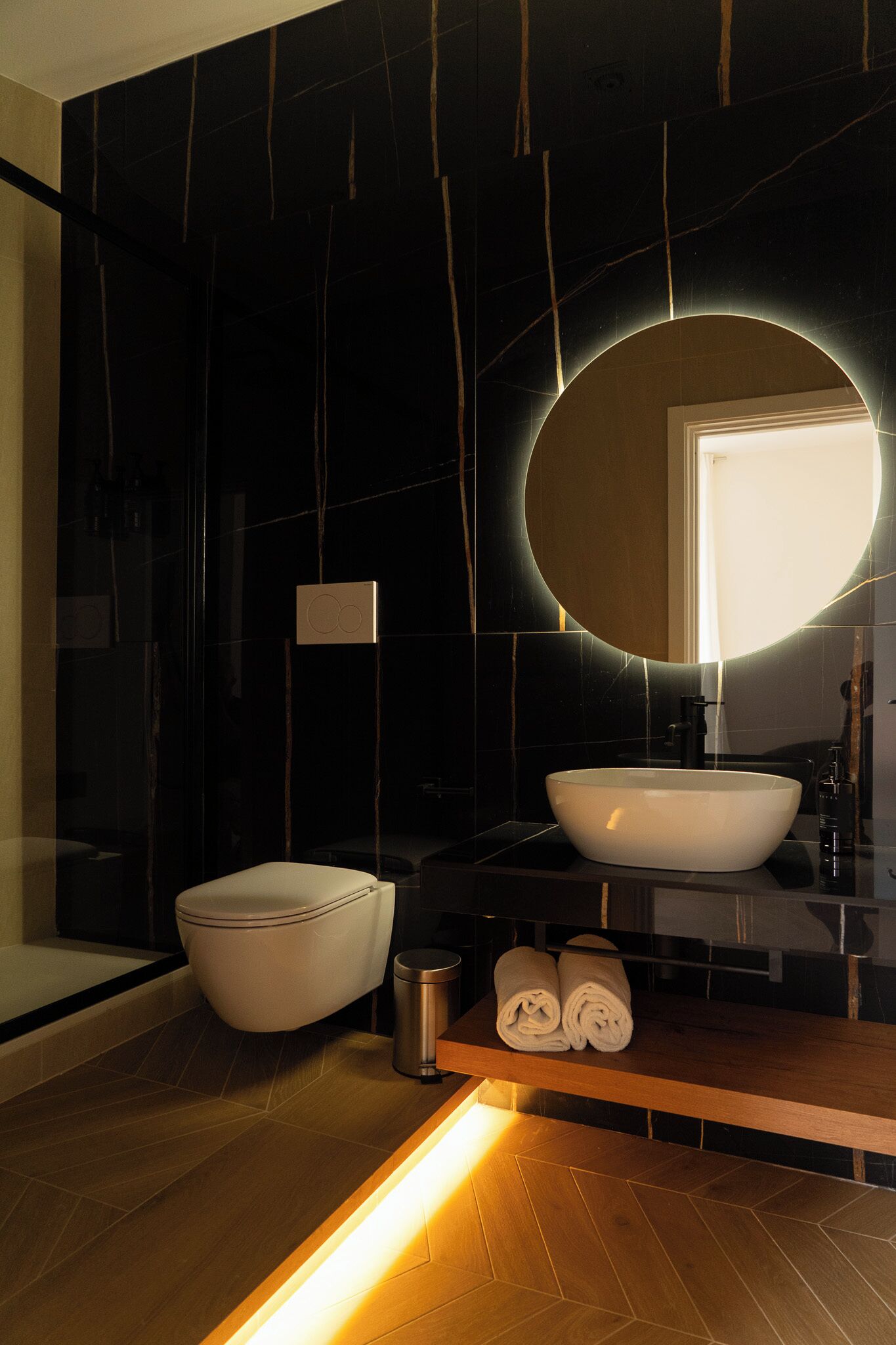 A modern bathroom with a large mirror, a white sink, and a toilet.