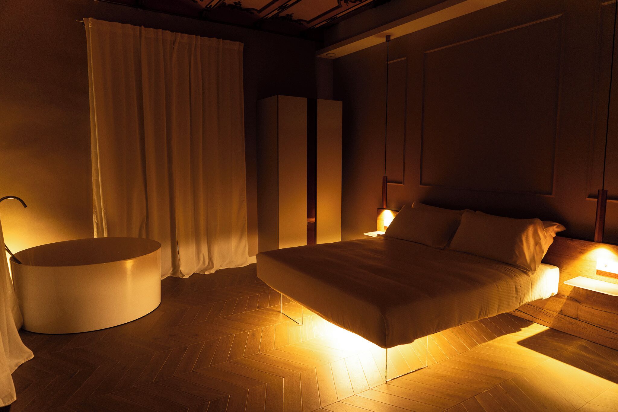 Un dormitorio con cama, mesita de noche y una silla redonda.