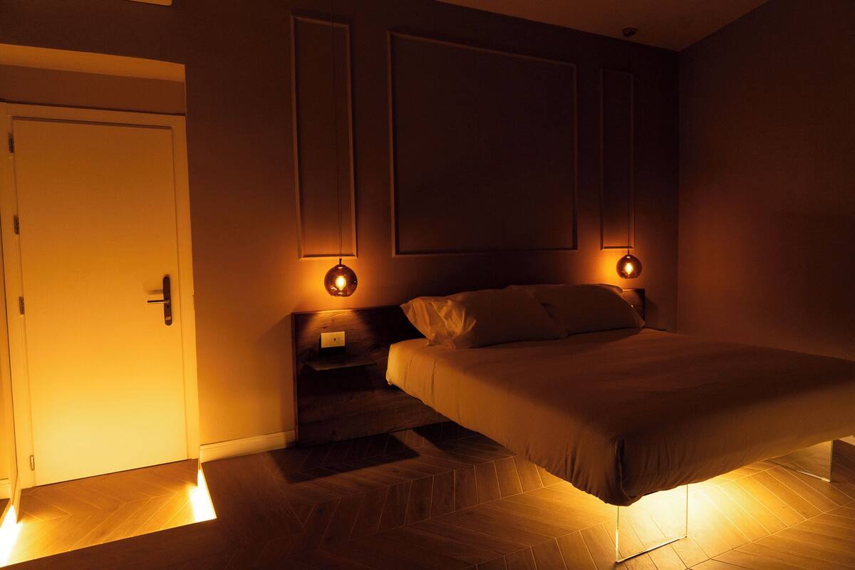 A bedroom with a bed, nightstands, and wall-mounted lamps.