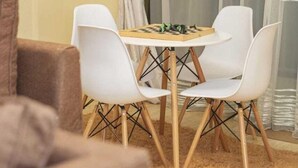 Une pièce chaleureuse avec une petite table ronde et deux chaises blanches, un canapé marron et un élément décoratif doré accroché au mur.