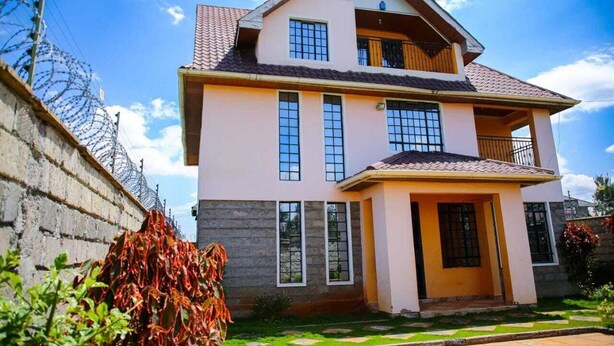 Une maison à deux étages avec un balcon, un toit en tuiles et un jardin à l’avant.
