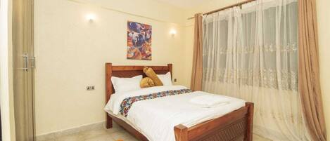 A bedroom with a wooden bed, a colorful rug, and a painting on the wall.