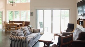 Un salon spacieux avec un canapé à rayures, une table basse en bois et un téléviseur fixé au mur.