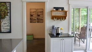Une cuisine moderne avec des meubles blancs, une machine à café et un meuble à bouteilles.