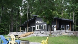 Une cabane avec un escalier en pierre menant à une terrasse, le tout entouré d’arbres.