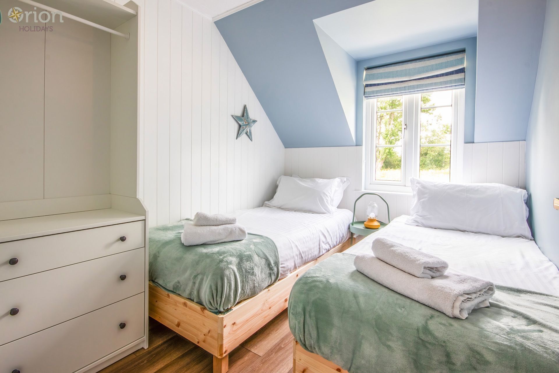 Een slaapkamer met twee bedden, een garderobe, ster decoratie en een raam met uitzicht.