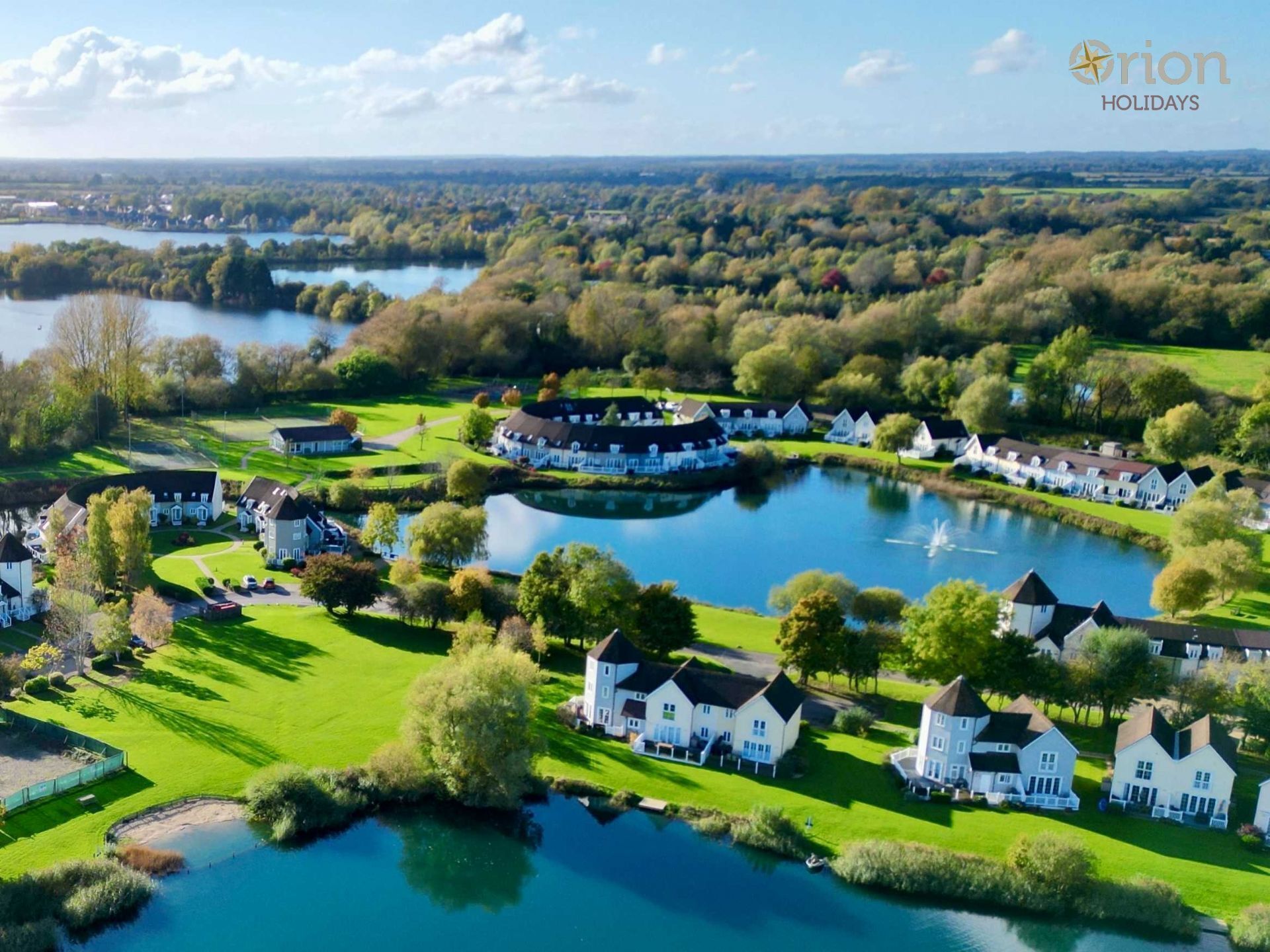 A lakeside resort with white buildings, a central lake, and surrounding greenery.