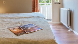 A bedroom with a bed, a window, a radiator, and a book on the bed.