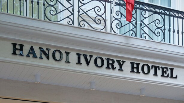 L’entrée de l’hôtel Hanoi Ivory, avec un grand escalier et une enseigne au-dessus de la porte.