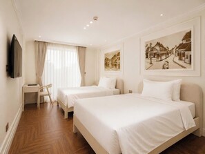 Habitación de hotel con dos camas, un escritorio, una silla y obras de arte en las paredes.