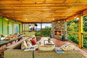 Un espace extérieur accueillant, aménagé avec des meubles en osier, une cheminée en pierre et offrant une vue sur le paysage.