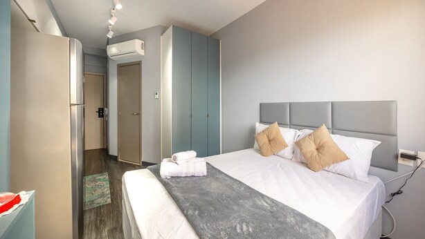 A hotel room with a bed, a grey throw blanket, a white bedside table, and a wardrobe. - Beautiful studio in São Caetano Ap610 (São Caetano do Sul)