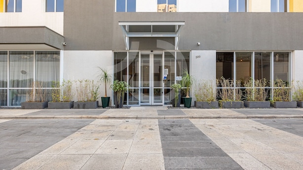 A modern building with a glass entrance, potted plants, and a number '300' sign.