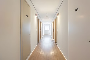 A long, narrow hotel corridor with wooden flooring and white walls. - Beautiful Studio São Caetano Barcelona ap412 (São Caetano do Sul)