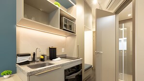 A compact kitchen with a built-in microwave, a sink, and a stove. - Beautiful studio in São Caetano ap614 (São Caetano do Sul)