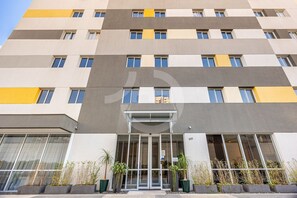 Een meerlaags gebouw met een moderne gevel, grote ramen en een centrale ingang met glazen deuren.