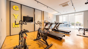 A gym with exercise equipment, a television, and large windows.