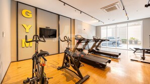 A gym with exercise equipment, a television, and large windows. - Modern studio in São Caetano Ap709 (São Caetano do Sul)