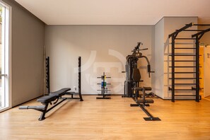 Une salle de sport équipée d’un banc, d’un support à poids et d’une barre de traction.