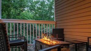 A patio with a stone fire feature, outdoor furniture, and a wooden railing.