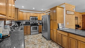 A kitchen with wooden cabinets, stainless steel appliances, a granite countertop, and a sign that says "ADVENTURE".