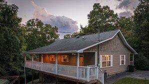 A two-story house with a covered porch and a small deck.