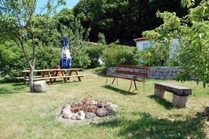 Ein Picknickbereich mit einem Steingrill, einem Picknicktisch und einer Bank.