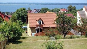 A residential area with houses, a grassy yard, and a body of water in the background.