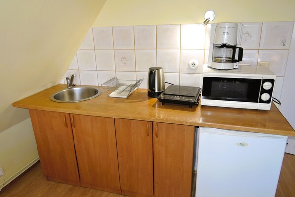 A compact kitchen with a sink, a coffee maker, a microwave, and a small refrigerator.