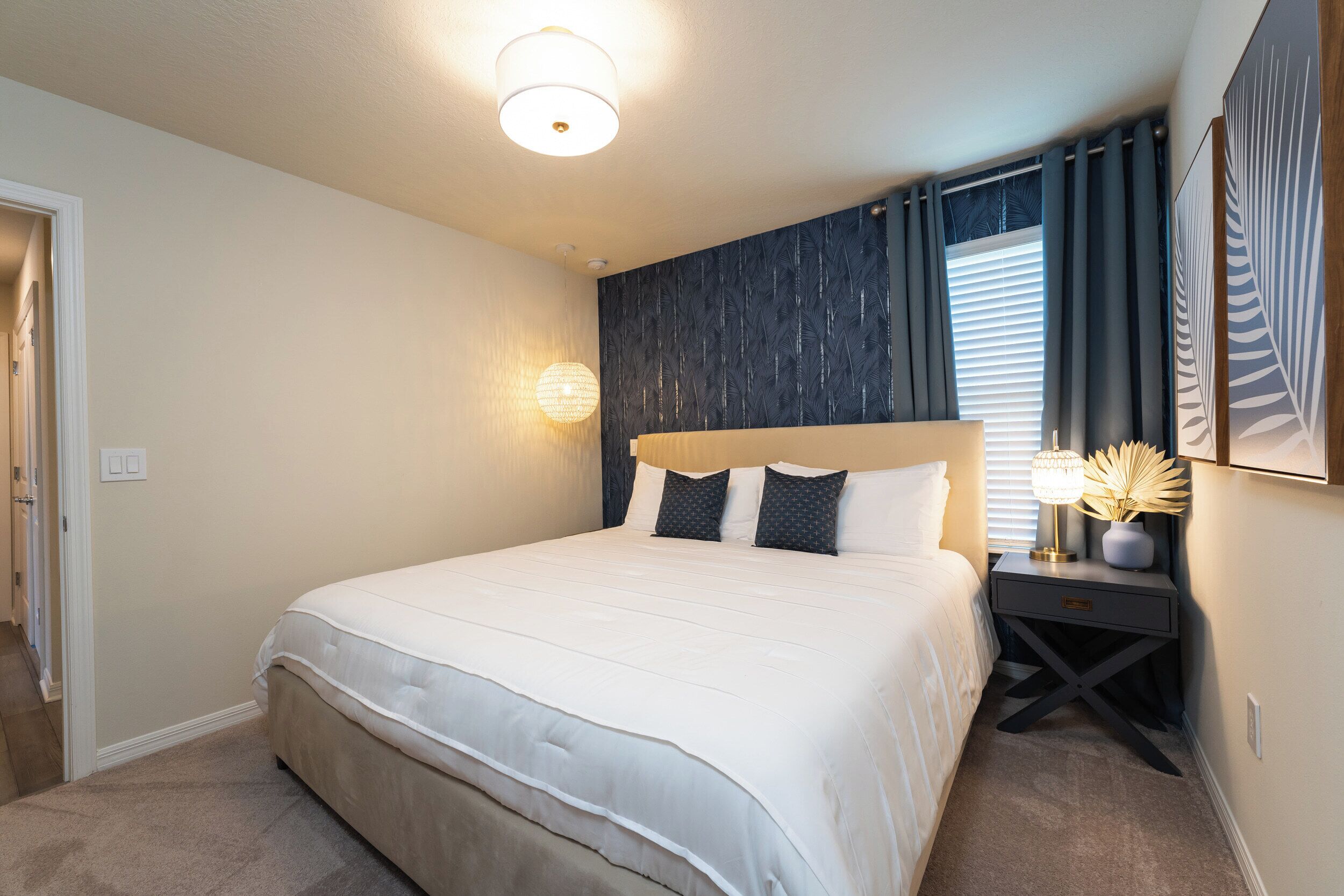 A neatly made bed with a headboard, a bedside table with a lamp, and a wall-mounted light fixture.