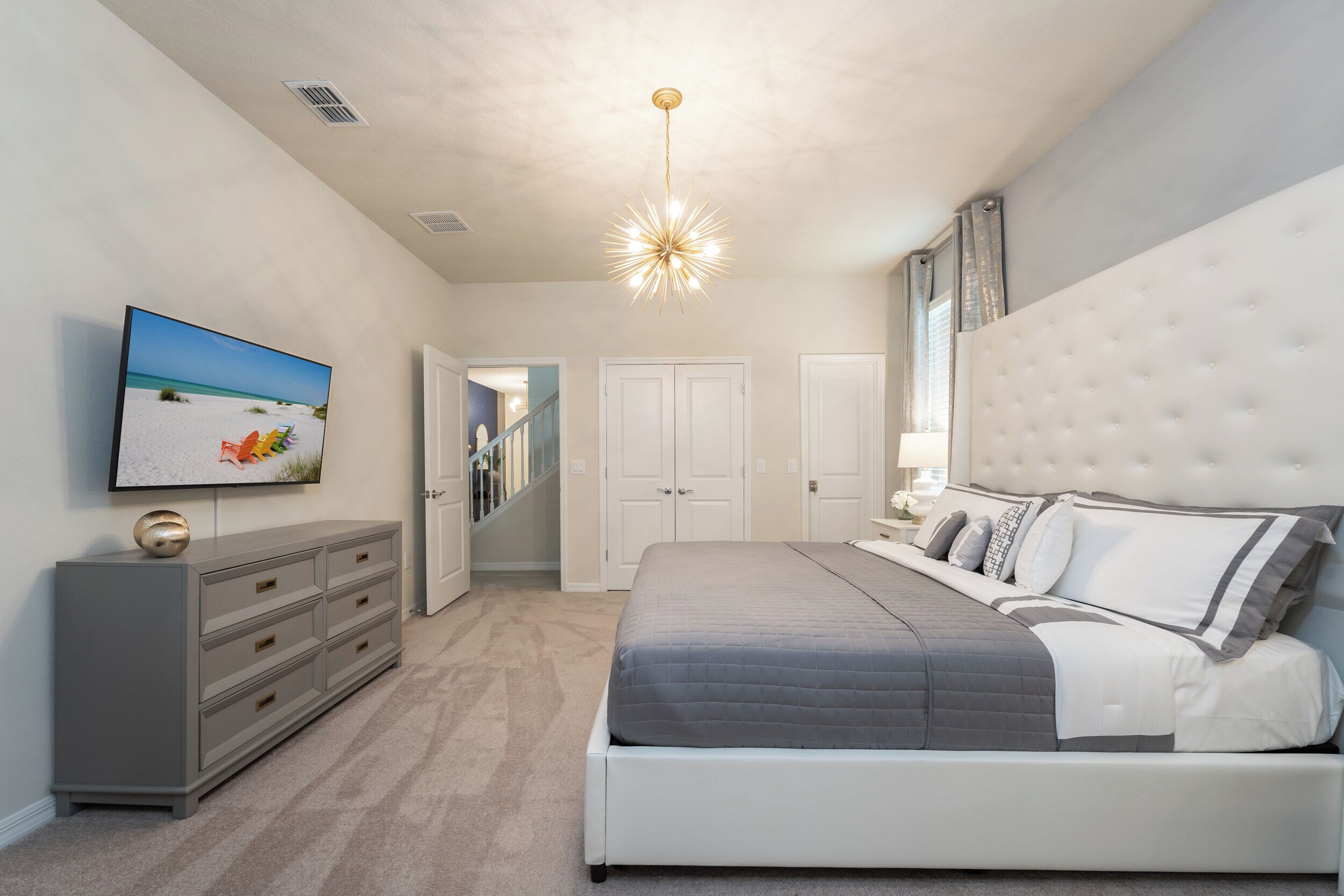 Een slaapkamer met een bed, een dressoir, een televisie en een trap.