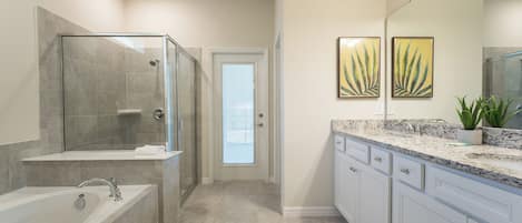 A modern bathroom with a glass-enclosed shower, a freestanding bathtub, and a vanity with a marble countertop.