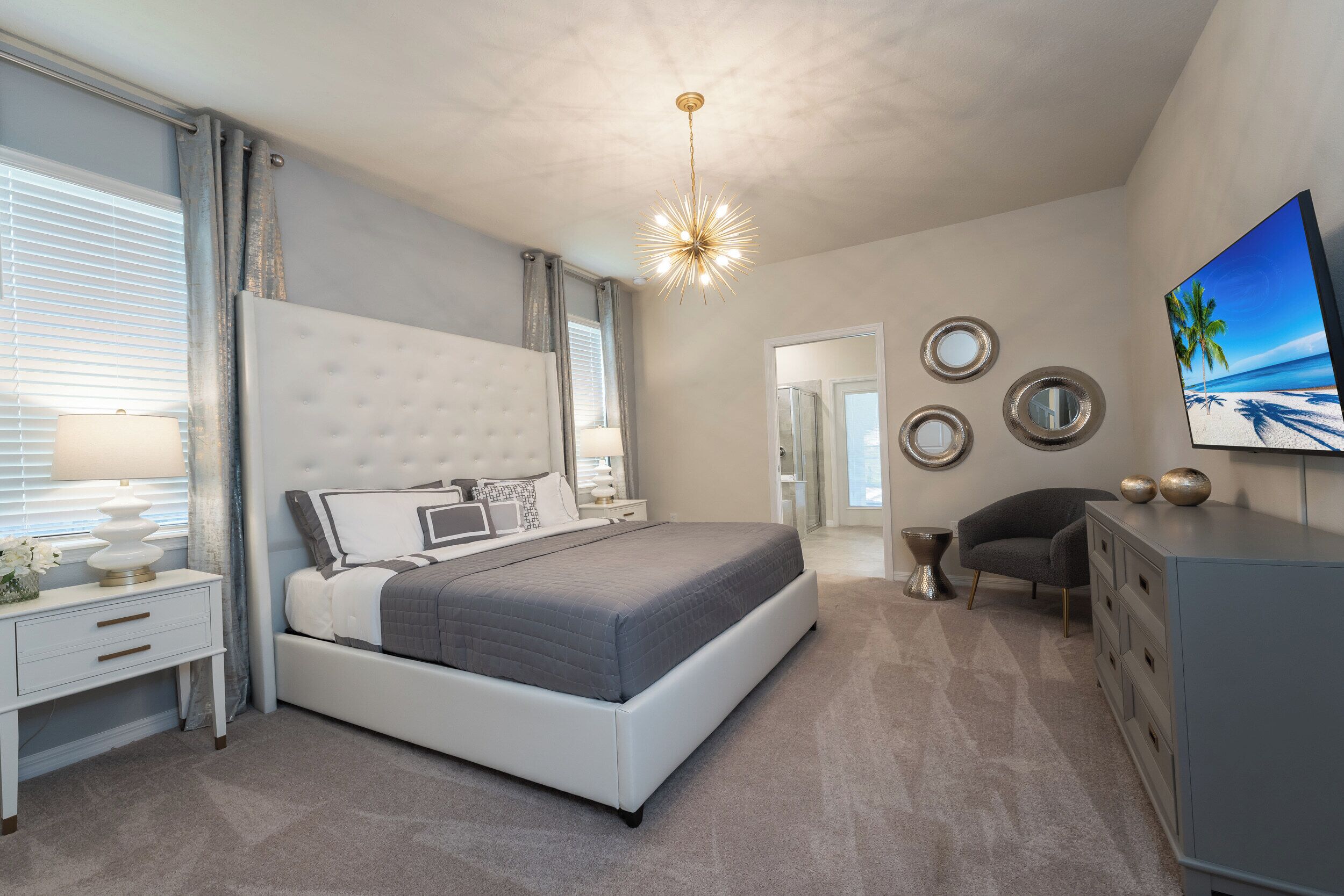 A modern bedroom with a large bed, bedside tables, a dresser, and a ceiling light fixture.