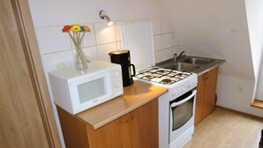Une cuisine compacte équipée d’un four à micro-ondes, d’une machine à café, d’une cuisinière et d’un évier.