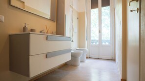 Een badkamer met een wit wastafelmeubel, toilet en grote spiegel.
