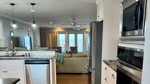 A modern kitchen with a central island, stainless steel appliances, and a view to the living area. - Oceanfront w/ sandy beach all day! 4100sq ft. Retreat w/ Private walk, Pet’s ok! (Fripp Island)