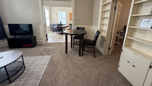 Un salon avec un téléviseur, une table à manger et une bibliothèque.