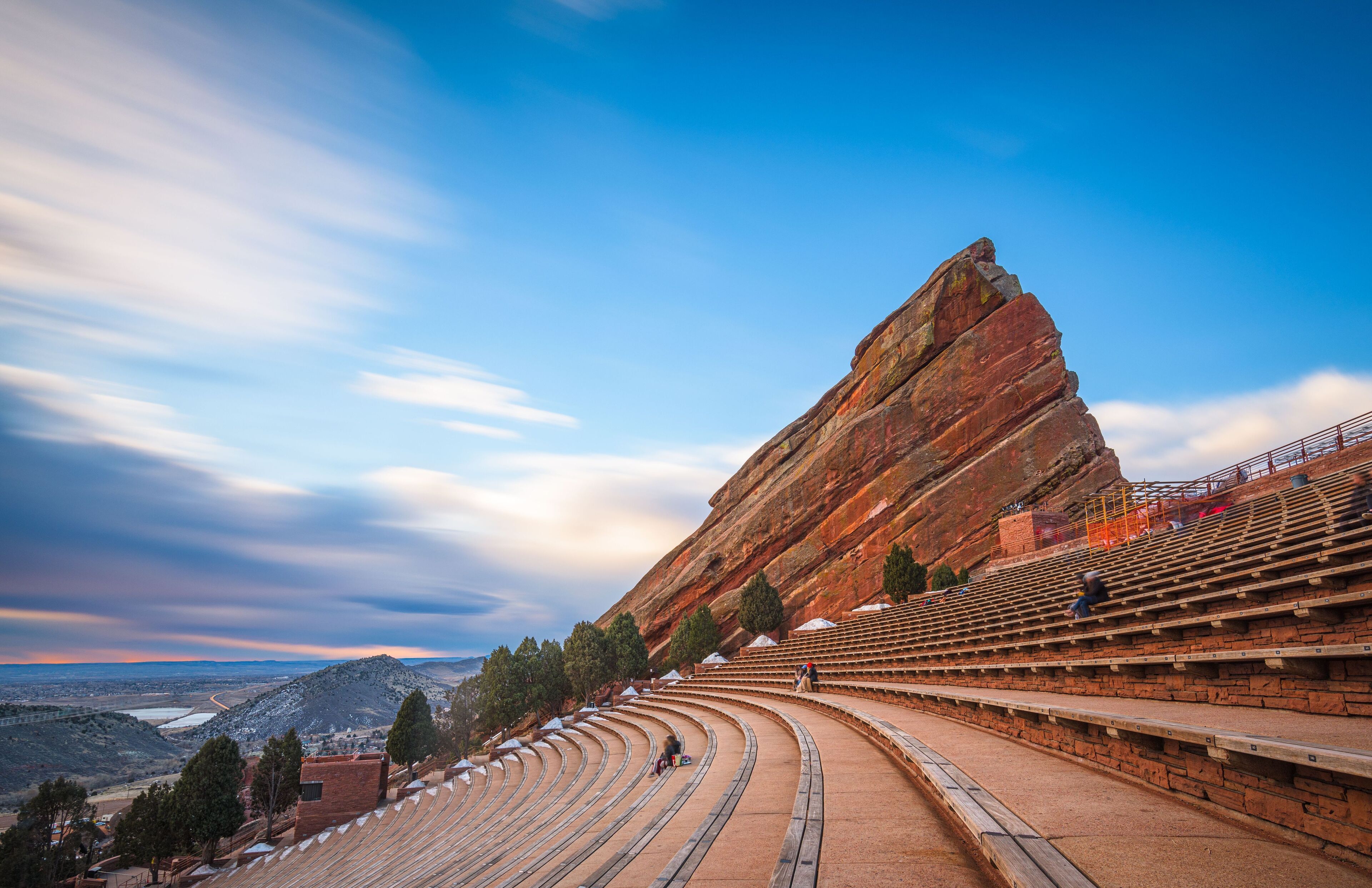 An outdoor amphitheater with tiered seating and a large rock formation.